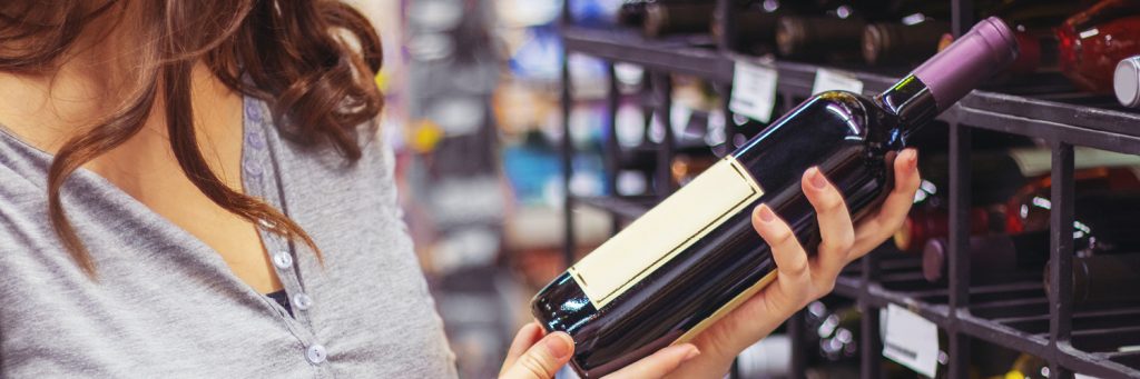 mujer sostiene una botella de vino en el pasillo de la tienda